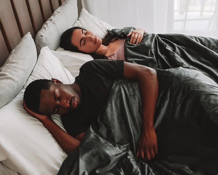 a couple sleeping under a grey weighted blanket