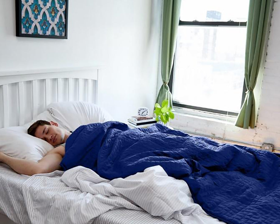a man sleeping under a blue weighted blanket