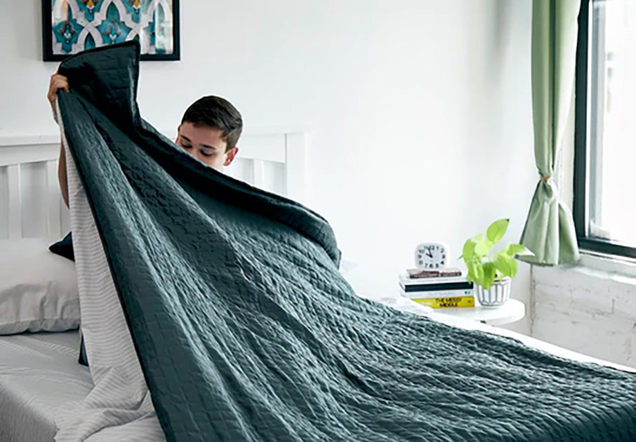 a woman pulling a green weighted blanket over herself