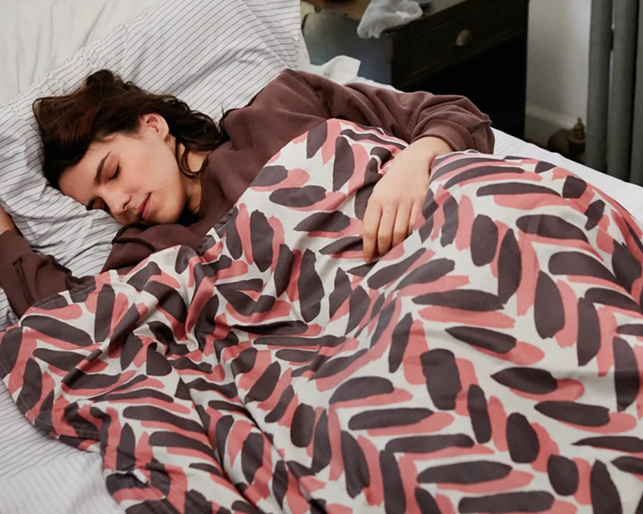a woman sleeping under a chevron patterned weighted blanket