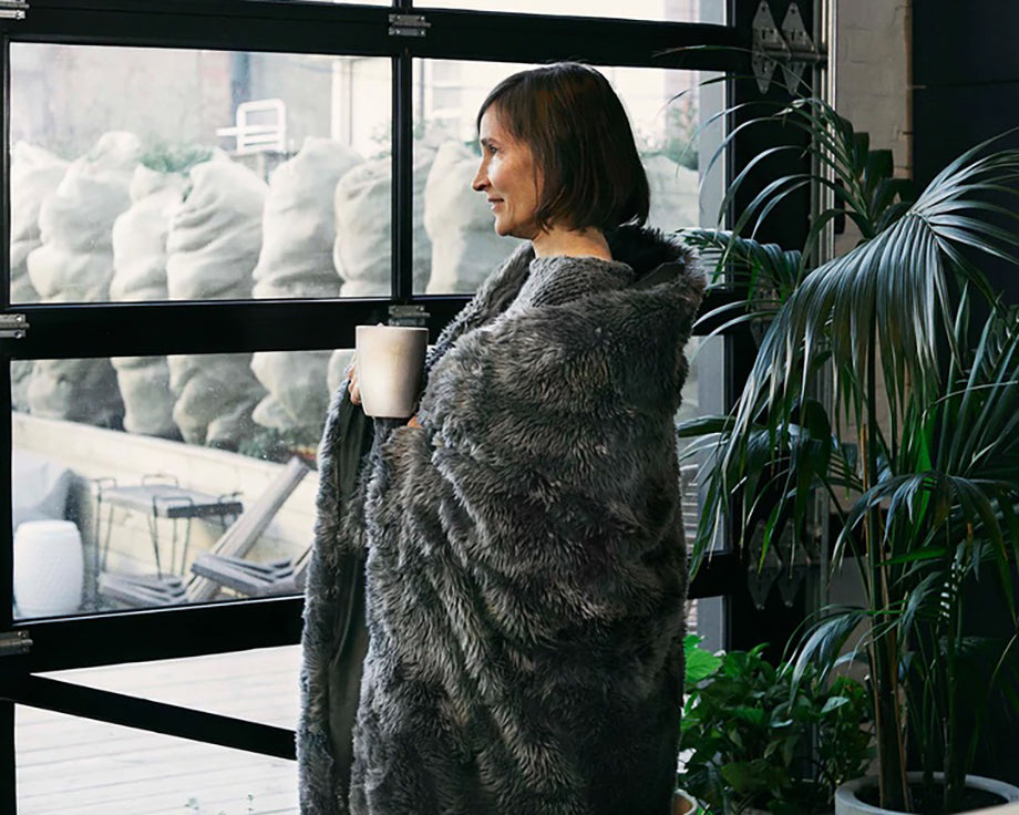 a woman with a mug wrapped in a fuzzy weighted blanket