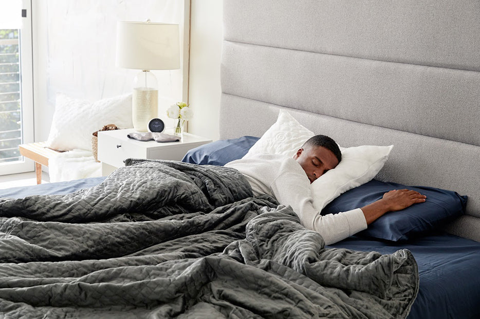 a man asleep under a grey weighted blanket
