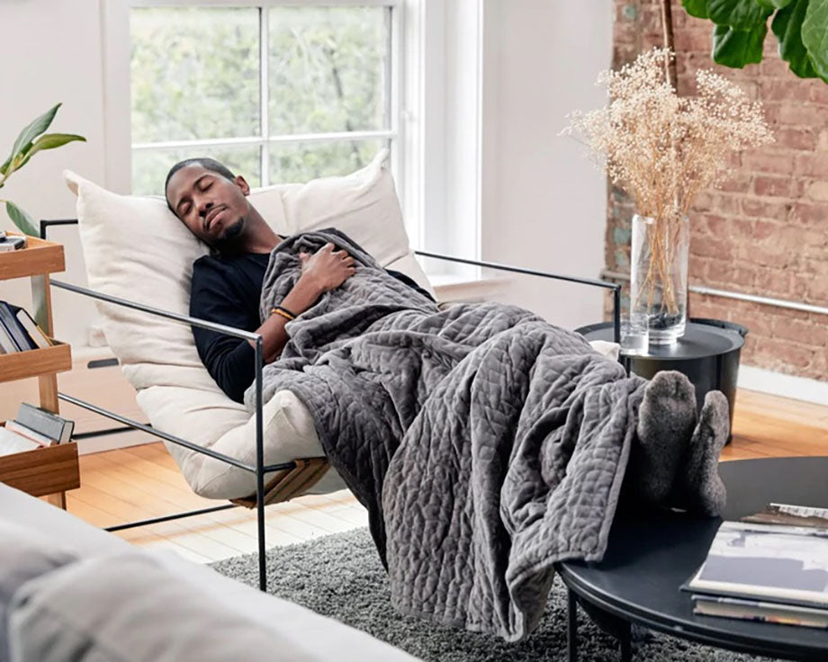 man asleep under blanket in chair