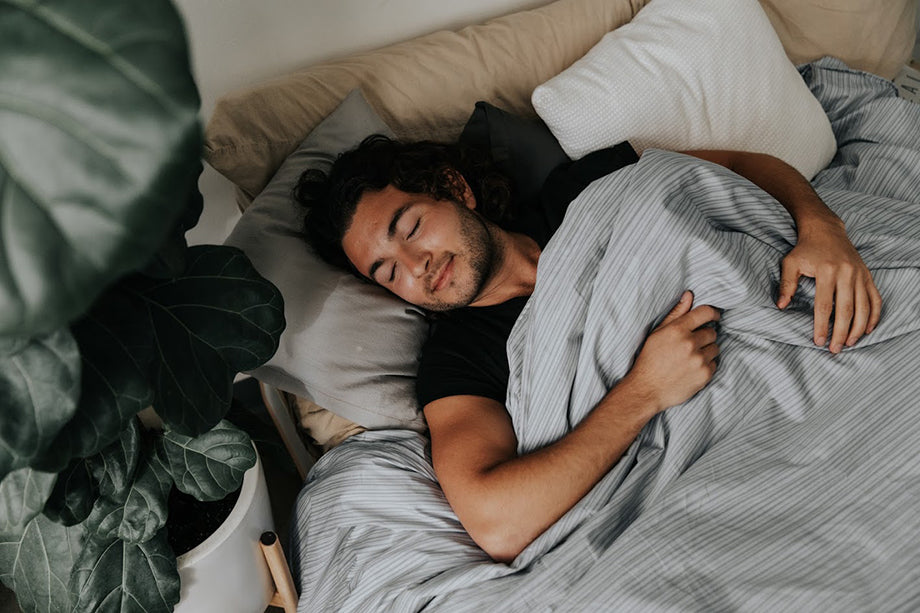 a man sleeping under a gray pinstripe weighted blanket