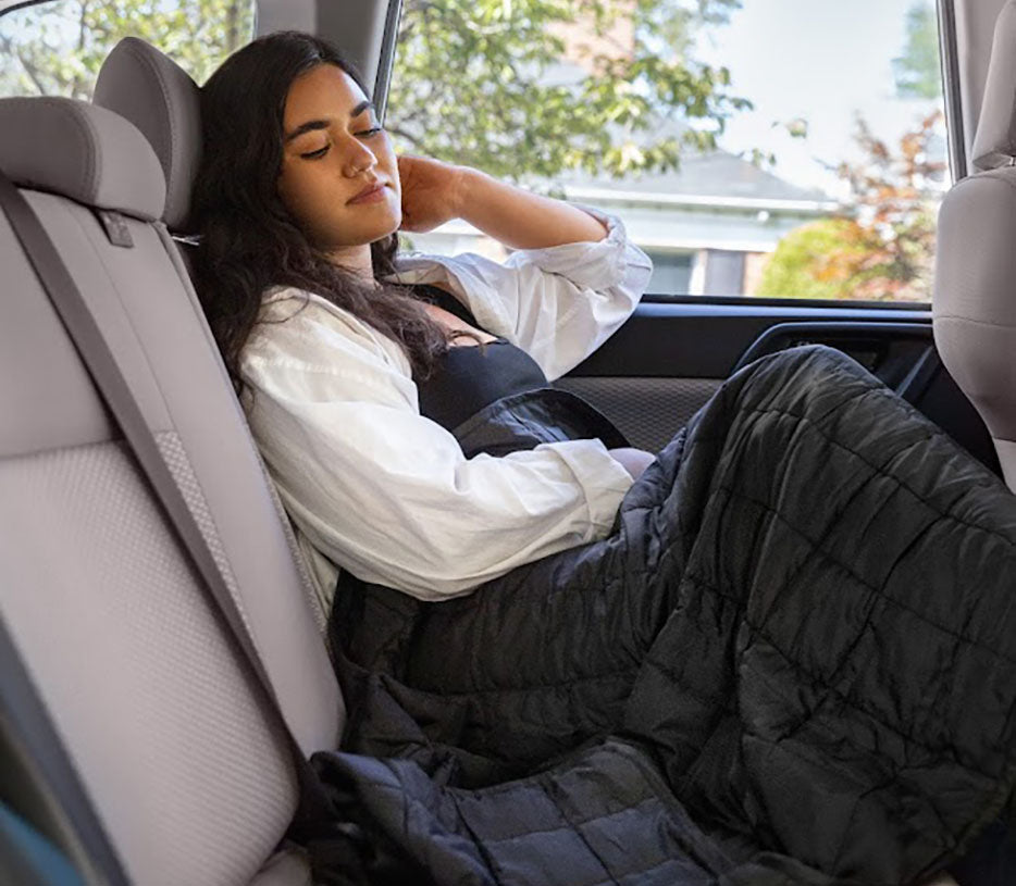 a woman using a weighted blanket in the back of a car