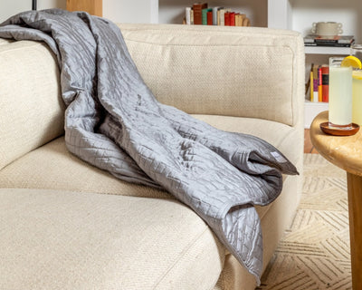 A Classic Grey Gravity Weighted Cooling Blanket draped over a sofa - #color_classic-grey