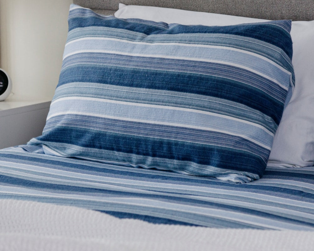 Closeup of sheets and pillows fitted with blue striped cozy bedding #color_blue-stripe