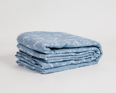 Blue sheets with printed penguins folded against a white backdrop #color_penguins
