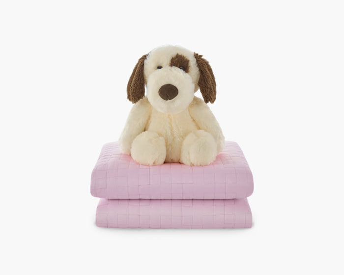 Light pink weighted blanket for kids folded with a plushie stacked on top