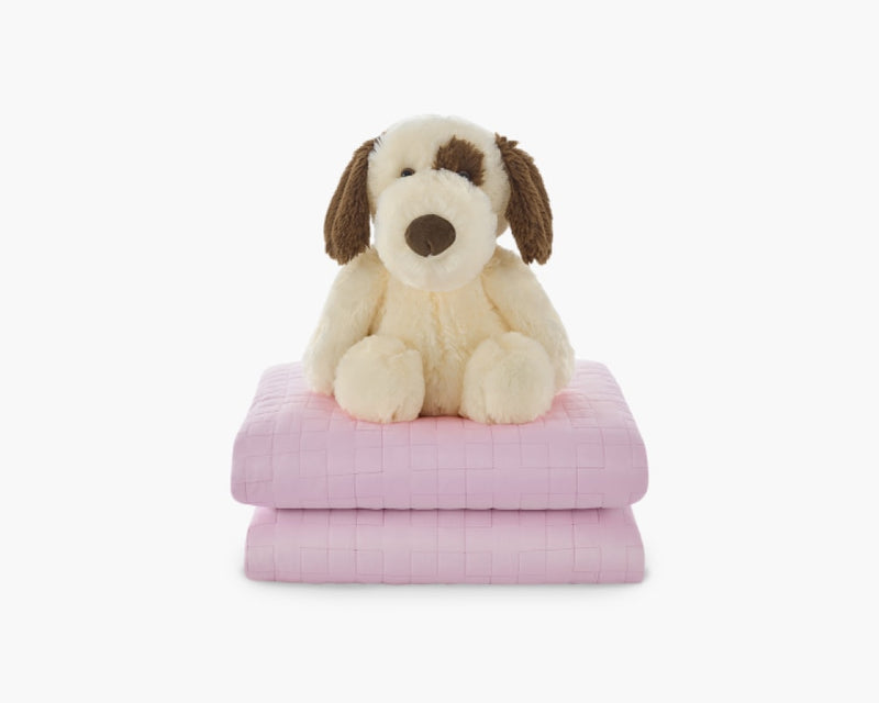 Light pink weighted blanket for kids folded with a plushie stacked on top