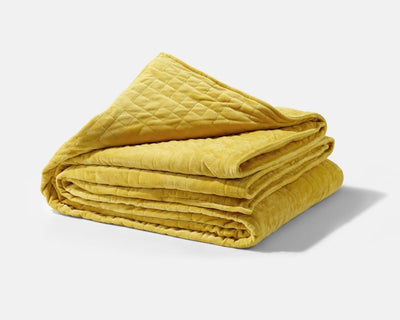 Original weighted blanket by Gravity in a plush gold fabric folded against a white backdrop - #color_gold