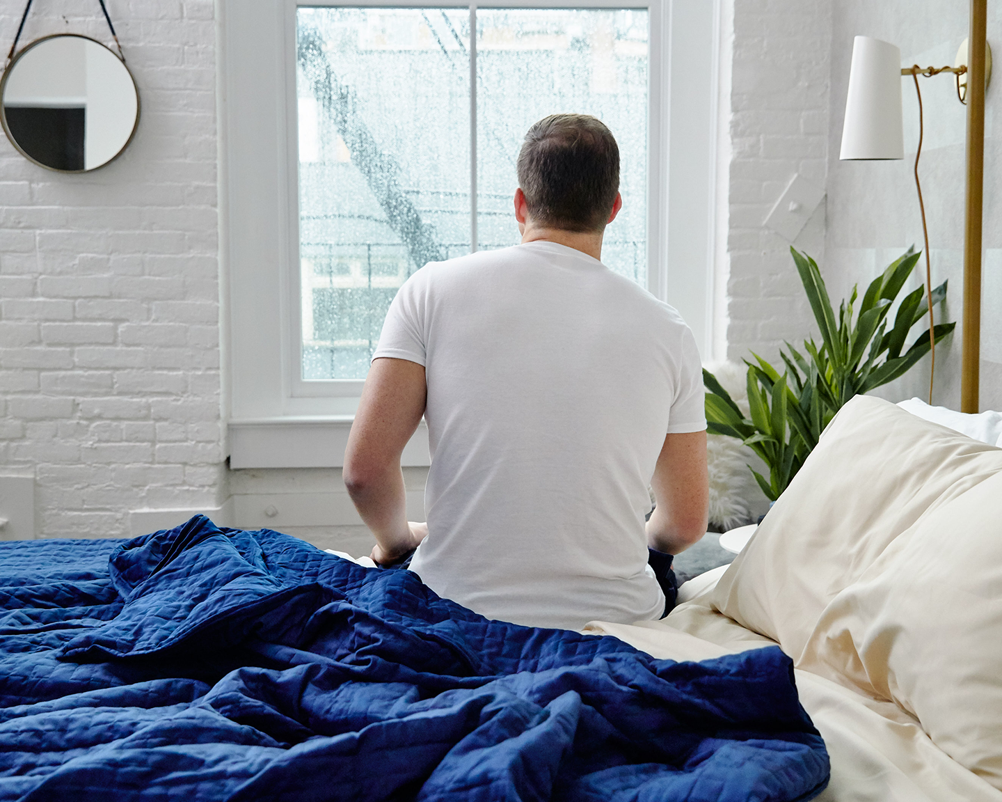 Man sitting up in bed, next to Navy Cooling gravity Blanket