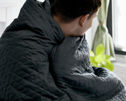 Man with Grey gravity cooling Blanket wrapped around his shoulders.